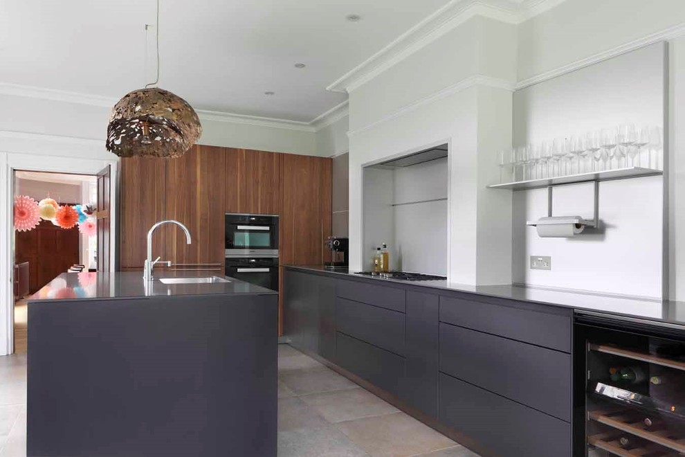 Inspiration for a large contemporary galley enclosed kitchen in London with black appliances and an island.