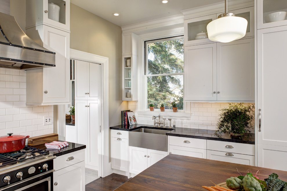 Exempel på ett avskilt, mellanstort klassiskt u-kök, med en rustik diskho, luckor med infälld panel, vita skåp, granitbänkskiva, vitt stänkskydd, stänkskydd i tunnelbanekakel, rostfria vitvaror, klinkergolv i keramik och en köksö