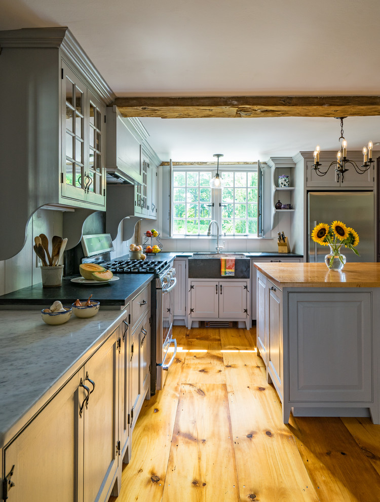 Large farmhouse l-shaped medium tone wood floor eat-in kitchen photo in Boston with a farmhouse sink, recessed-panel cabinets, gray cabinets, soapstone countertops, stainless steel appliances and an island