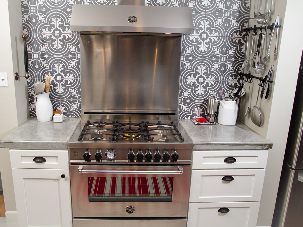 Foto på ett litet lantligt kök, med en rustik diskho, skåp i shakerstil, vita skåp, bänkskiva i betong, grått stänkskydd, stänkskydd i cementkakel, rostfria vitvaror, målat trägolv, en köksö och grått golv