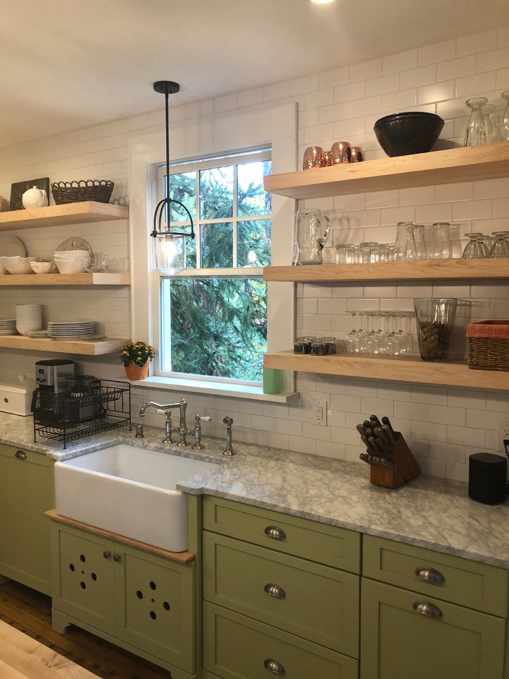 Inredning av ett lantligt mellanstort grå grått kök, med en rustik diskho, skåp i shakerstil, gröna skåp, granitbänkskiva, vitt stänkskydd, stänkskydd i tunnelbanekakel, rostfria vitvaror, mellanmörkt trägolv, en köksö och brunt golv