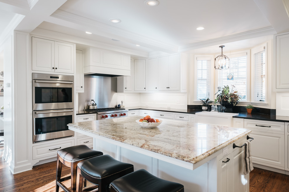 Inspiration for a medium sized traditional l-shaped kitchen/diner in Minneapolis with raised-panel cabinets, white cabinets, onyx worktops, integrated appliances, light hardwood flooring, an island and a belfast sink.
