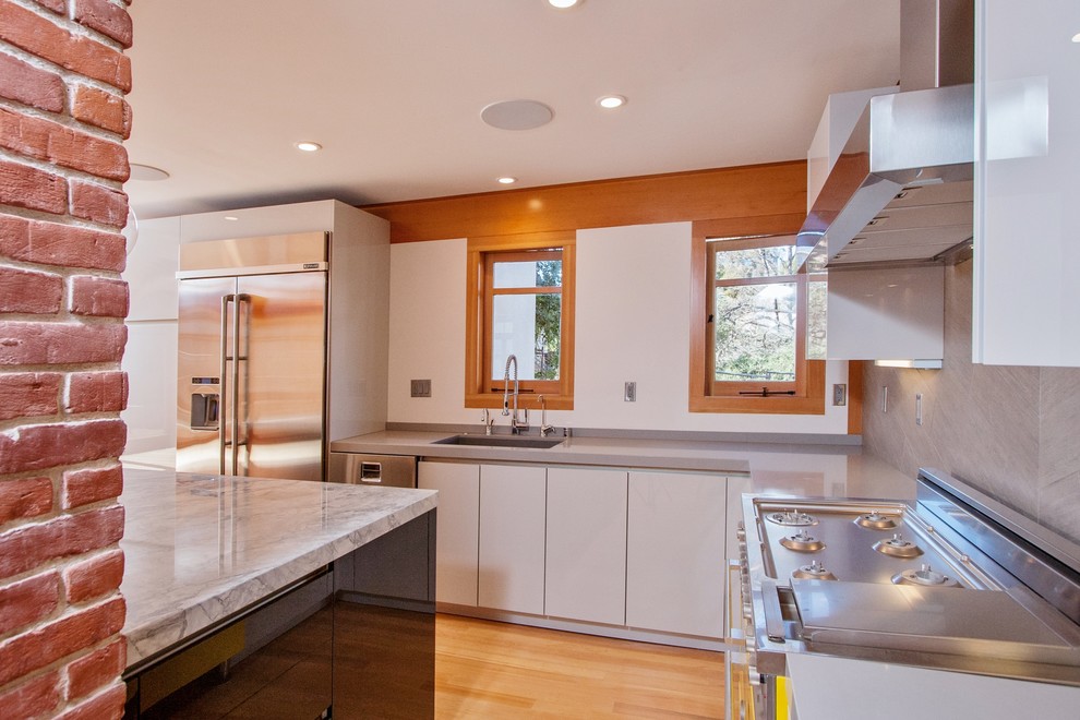 Mid-sized mid-century modern l-shaped light wood floor eat-in kitchen photo in San Diego with quartzite countertops, an undermount sink, flat-panel cabinets, white cabinets, gray backsplash, ceramic backsplash, stainless steel appliances and an island