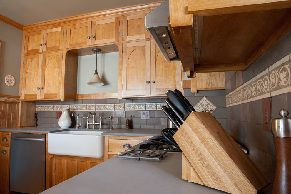 Foto på ett litet amerikanskt kök, med en rustik diskho, skåp i mellenmörkt trä, bänkskiva i täljsten, grått stänkskydd, stänkskydd i keramik, rostfria vitvaror, luckor med infälld panel, ljust trägolv och en halv köksö
