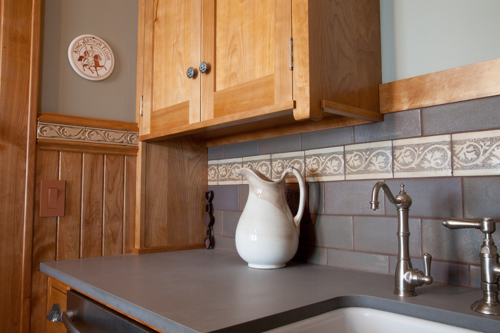 Idéer för att renovera ett litet amerikanskt kök, med en rustik diskho, skåp i mellenmörkt trä, bänkskiva i täljsten, grått stänkskydd, stänkskydd i keramik, rostfria vitvaror, luckor med infälld panel, ljust trägolv och en halv köksö