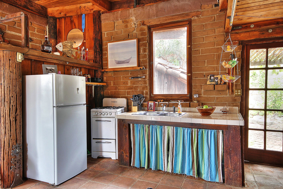 Foto på ett litet rustikt l-kök, med en dubbel diskho, öppna hyllor, kaklad bänkskiva och vita vitvaror