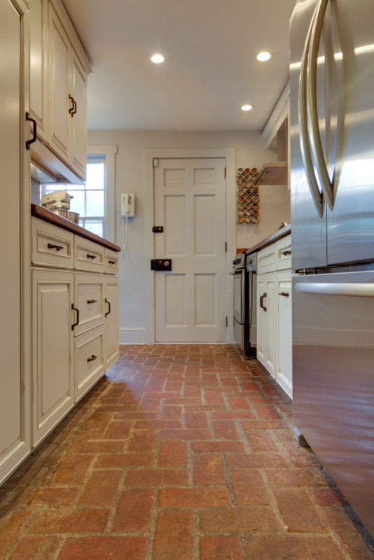 Inspiration for a small transitional galley brick floor enclosed kitchen remodel in DC Metro with a single-bowl sink, recessed-panel cabinets, beige cabinets, wood countertops, multicolored backsplash, stainless steel appliances and no island