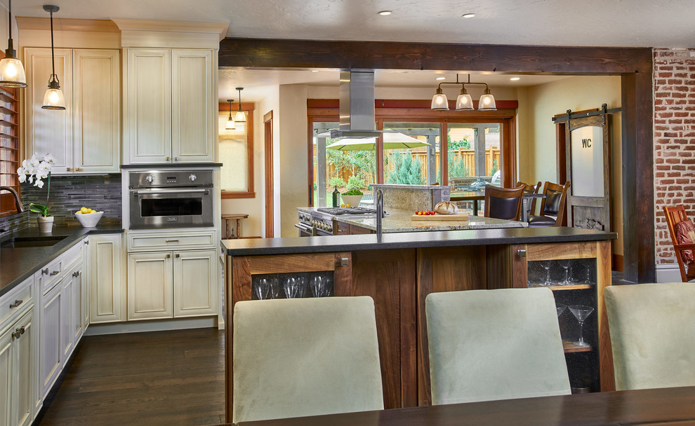 Foto på ett stort amerikanskt linjärt kök och matrum, med en enkel diskho, träbänkskiva, grått stänkskydd, stänkskydd i mosaik, rostfria vitvaror, mörkt trägolv, flera köksöar, brunt golv och luckor med infälld panel