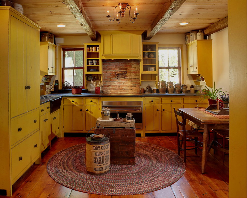 Foto di una cucina a L country chiusa con ante gialle, pavimento in legno massello medio, nessuna isola, lavello stile country e elettrodomestici colorati