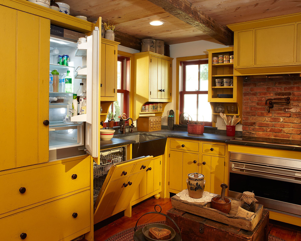 Свежая идея для дизайна: угловая кухня в стиле кантри с обеденным столом, с полувстраиваемой мойкой (с передним бортиком), желтыми фасадами, цветной техникой и паркетным полом среднего тона - отличное фото интерьера