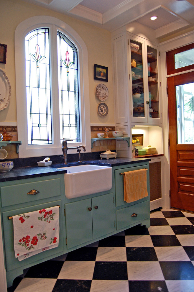 Lantlig inredning av ett kök, med en rustik diskho, blå skåp och flerfärgat golv
