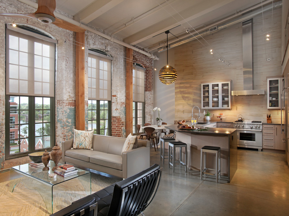 Inspiration for a mid-sized industrial l-shaped concrete floor and gray floor open concept kitchen remodel in Atlanta with an undermount sink, flat-panel cabinets, quartzite countertops, beige backsplash, stainless steel appliances, a peninsula, light wood cabinets and ceramic backsplash