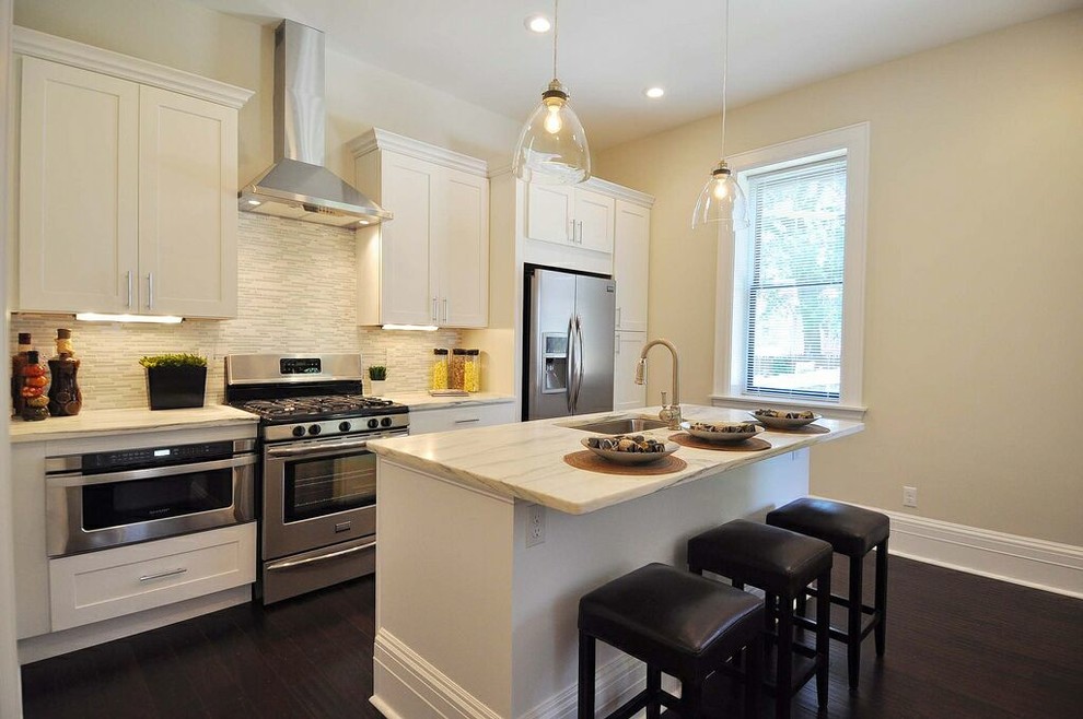 Mid-sized transitional galley dark wood floor and brown floor eat-in kitchen photo in St Louis with a single-bowl sink, shaker cabinets, white cabinets, marble countertops, white backsplash, mosaic tile backsplash, stainless steel appliances and an island