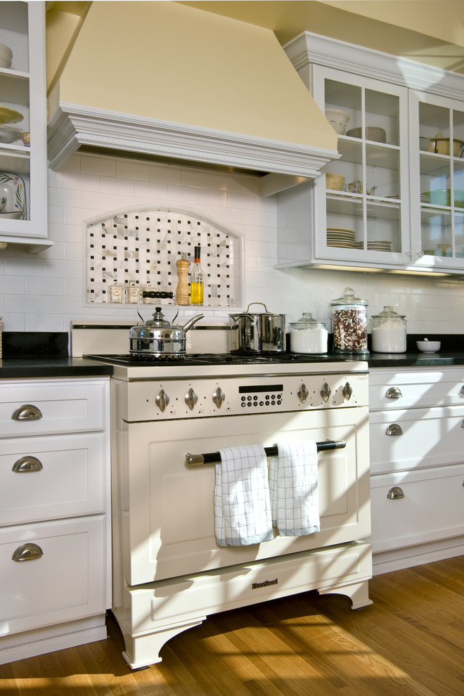 Klassische Küche mit Küchenrückwand in Weiß, Rückwand aus Metrofliesen, braunem Holzboden und weißen Elektrogeräten in San Diego