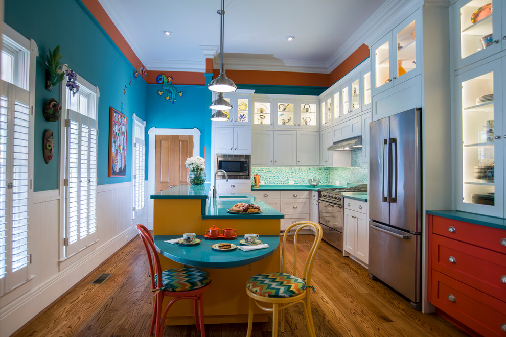 Exemple d'une grande cuisine américaine parallèle exotique avec un évier encastré, un placard à porte shaker, un électroménager en acier inoxydable, un sol en bois brun, un plan de travail en quartz modifié, une crédence bleue, une crédence en mosaïque, îlot, des portes de placard blanches et un plan de travail turquoise.