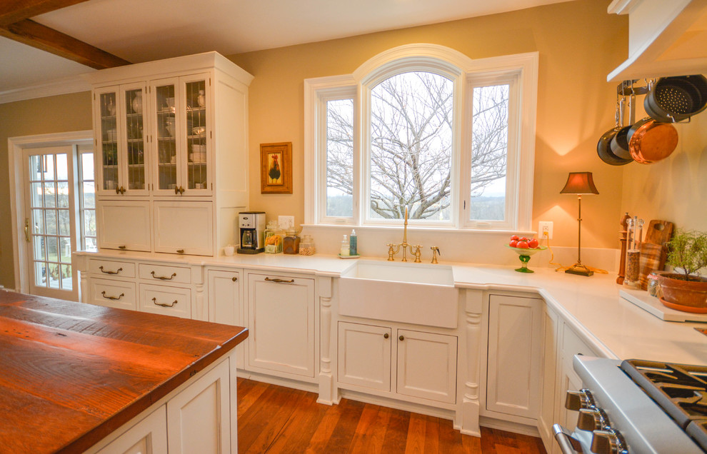 Foto på ett stort lantligt kök, med en rustik diskho, skåp i shakerstil, vita skåp, bänkskiva i kvarts, vitt stänkskydd, stänkskydd i porslinskakel, integrerade vitvaror, mellanmörkt trägolv, en köksö och rött golv