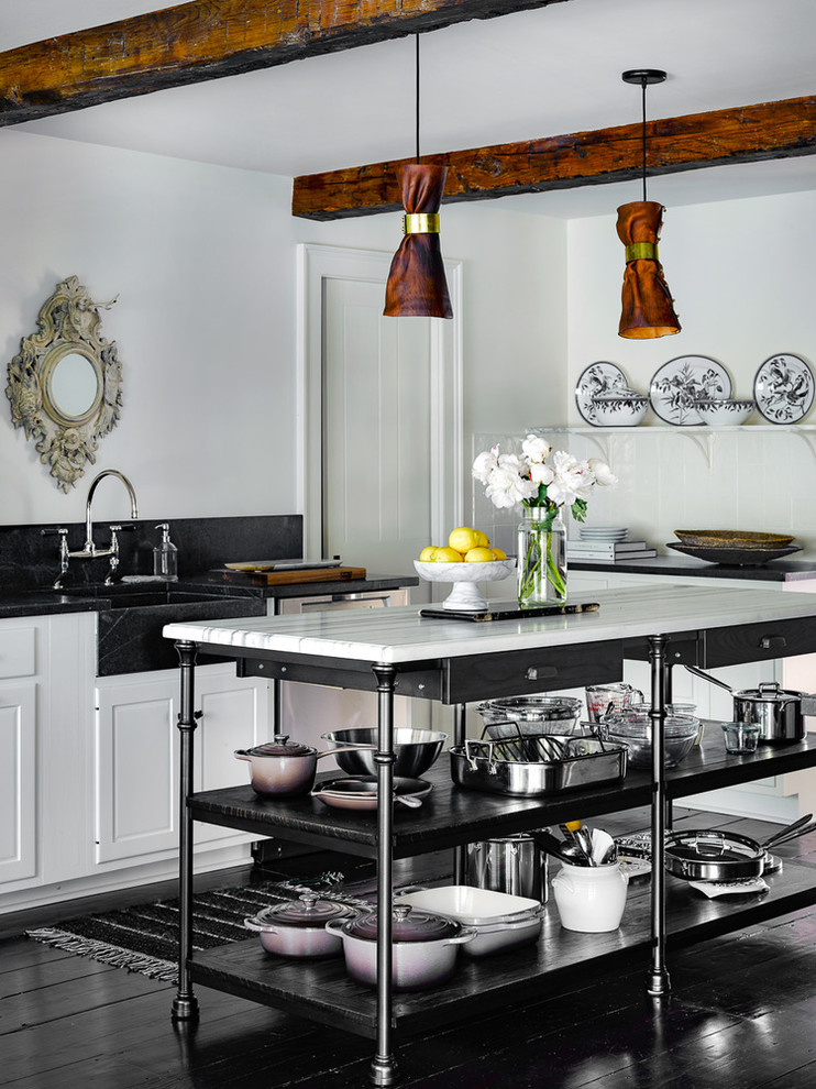 Immagine di un cucina con isola centrale country con lavello stile country, ante a filo, paraspruzzi nero e pavimento in legno verniciato