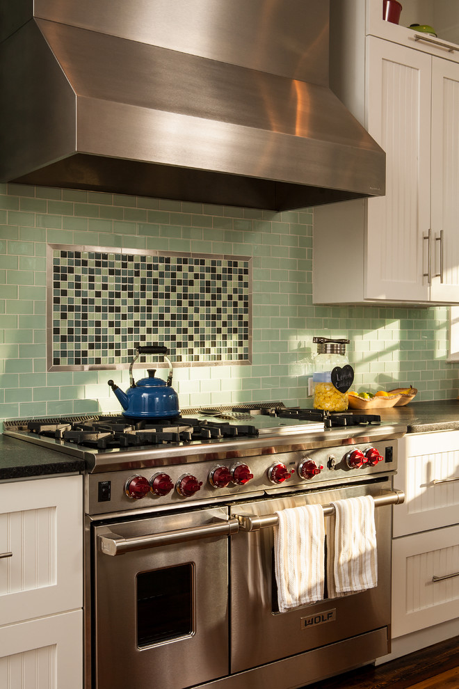На фото: кухня в стиле кантри с фартуком из плитки кабанчик, техникой из нержавеющей стали, зеленым фартуком и белыми фасадами