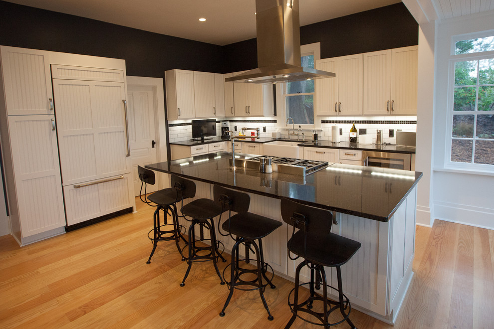 Bild på ett mellanstort funkis kök, med en rustik diskho, luckor med profilerade fronter, vita skåp, bänkskiva i kvarts, vitt stänkskydd, stänkskydd i keramik, rostfria vitvaror, mellanmörkt trägolv och en köksö
