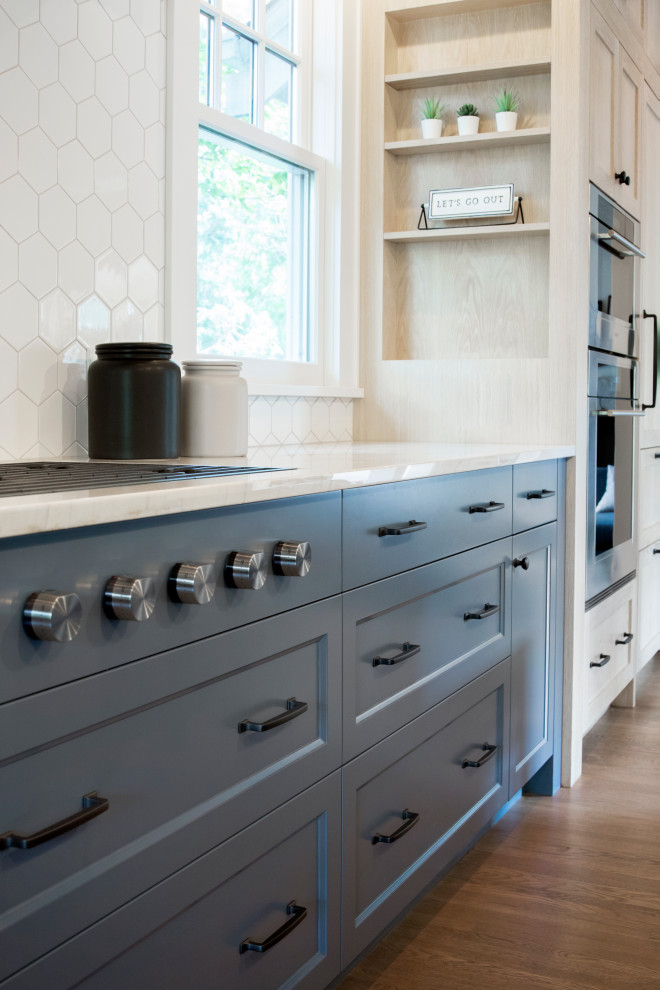ミネアポリスにある高級な巨大なトランジショナルスタイルのおしゃれなキッチン (アンダーカウンターシンク、落し込みパネル扉のキャビネット、青いキャビネット、御影石カウンター、白いキッチンパネル、セラミックタイルのキッチンパネル、パネルと同色の調理設備、無垢フローリング、青いキッチンカウンター) の写真