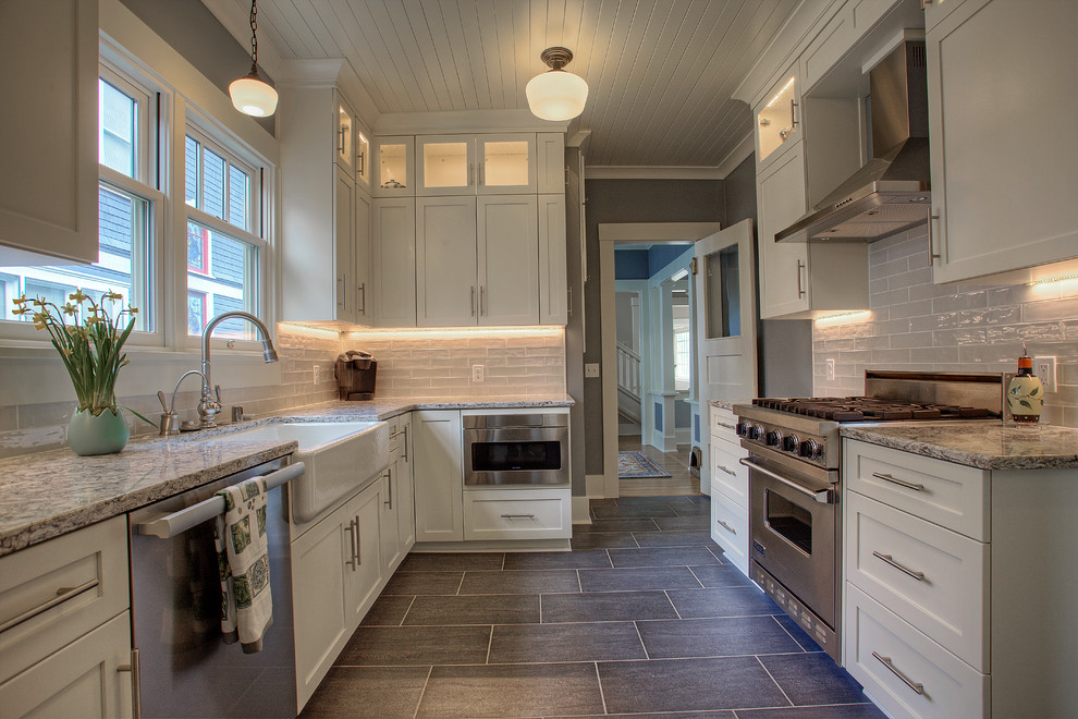 Large elegant galley porcelain tile and gray floor enclosed kitchen photo in Seattle with a farmhouse sink, shaker cabinets, white cabinets, quartzite countertops, gray backsplash, glass tile backsplash, stainless steel appliances and no island