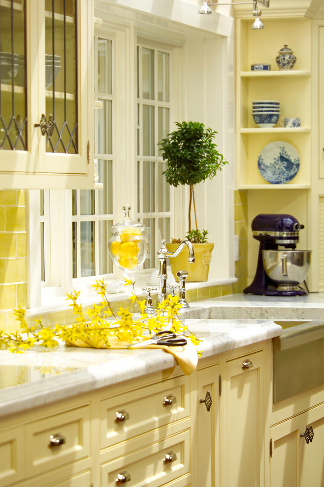 Inspiration for a timeless u-shaped enclosed kitchen remodel in Boston with a farmhouse sink, beaded inset cabinets, yellow cabinets, marble countertops, yellow backsplash, subway tile backsplash and stainless steel appliances