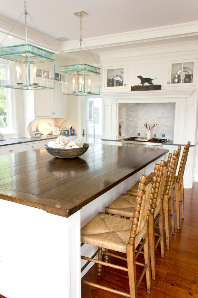 Example of a huge beach style u-shaped medium tone wood floor eat-in kitchen design in New York with white cabinets, wood countertops, gray backsplash and an island