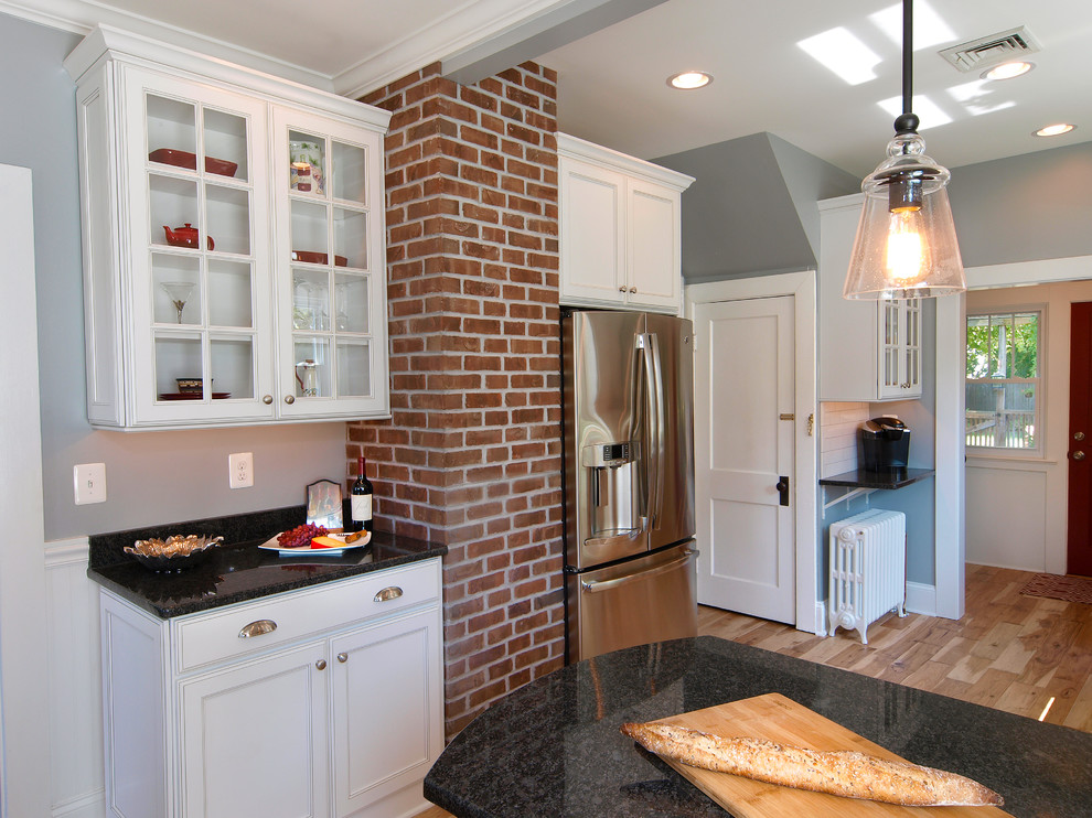 Foto di una cucina classica con ante bianche, top in granito e pavimento in legno massello medio
