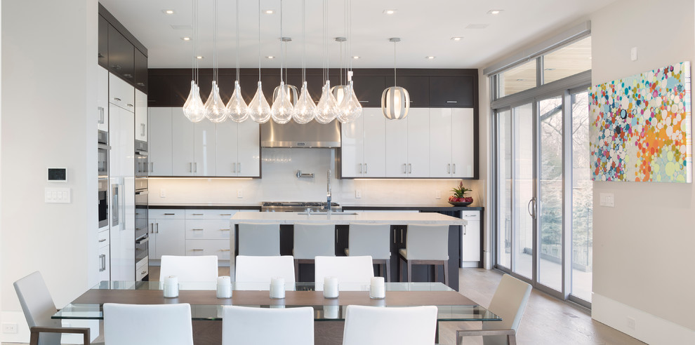 Inspiration for a large modern l-shaped kitchen/diner in Toronto with a double-bowl sink, flat-panel cabinets, white cabinets, marble worktops, white splashback, slate splashback, stainless steel appliances, light hardwood flooring, an island and yellow floors.