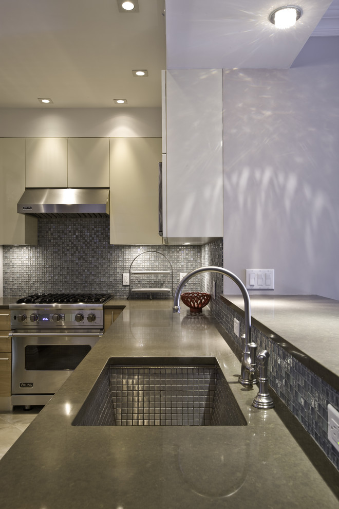 Example of a minimalist kitchen design in New York with stainless steel appliances, a single-bowl sink, flat-panel cabinets, medium tone wood cabinets, quartz countertops, mosaic tile backsplash and metallic backsplash