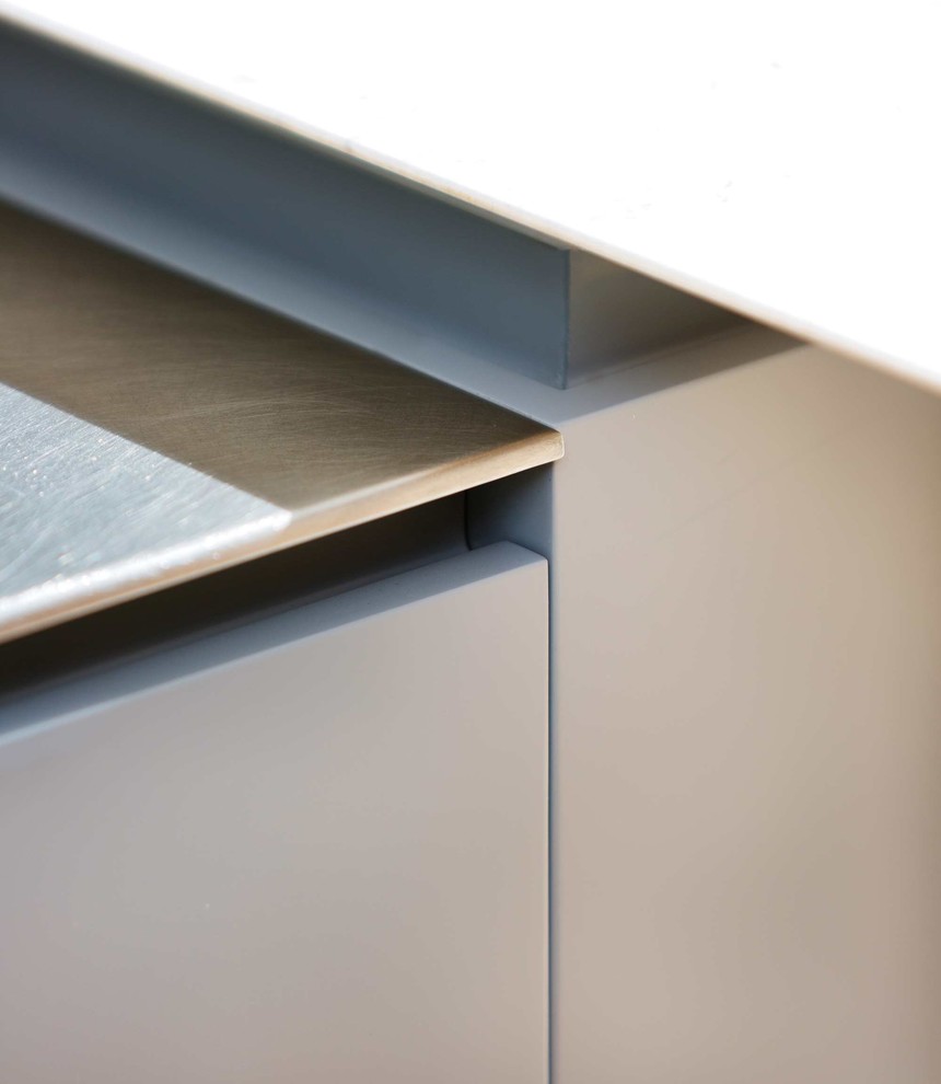 Modelo de cocina lineal contemporánea de tamaño medio con armarios con paneles lisos, electrodomésticos de acero inoxidable, suelo de madera clara y una isla