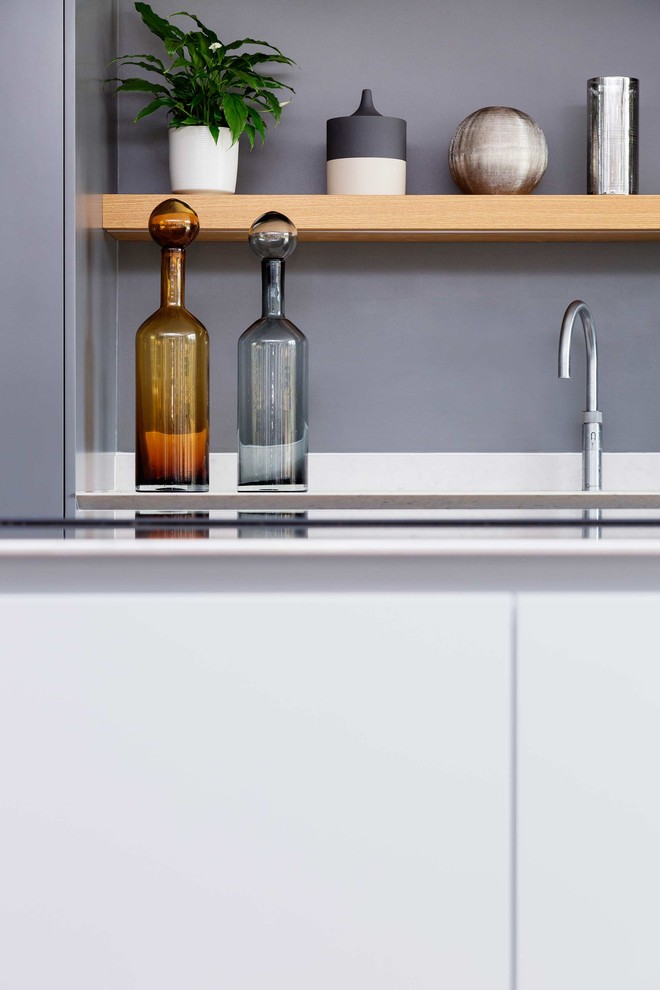 Einzeilige Moderne Küche mit flächenbündigen Schrankfronten, Küchengeräten aus Edelstahl, hellem Holzboden und Kücheninsel in London