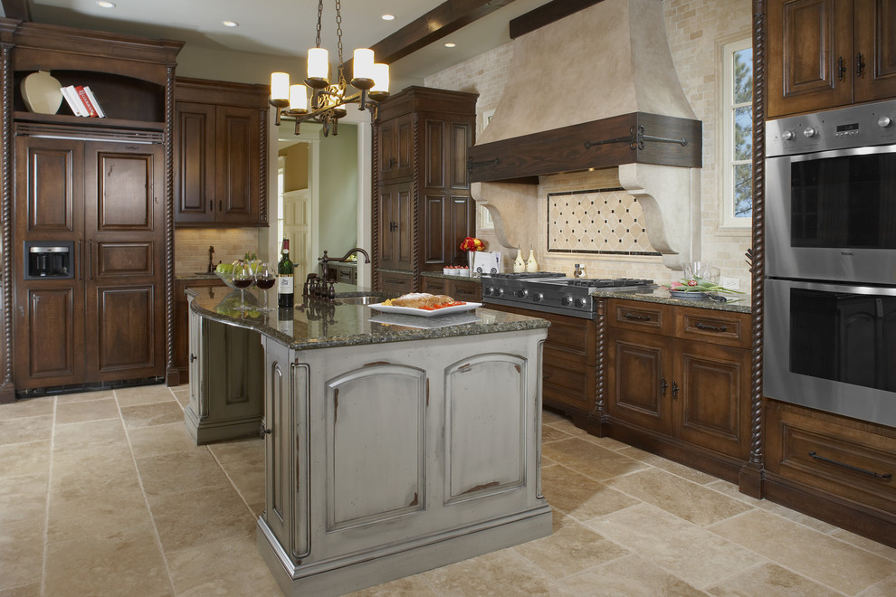Foto di una cucina classica con elettrodomestici da incasso, ante con bugna sagomata, top in granito, paraspruzzi beige, pavimento in travertino e paraspruzzi in travertino