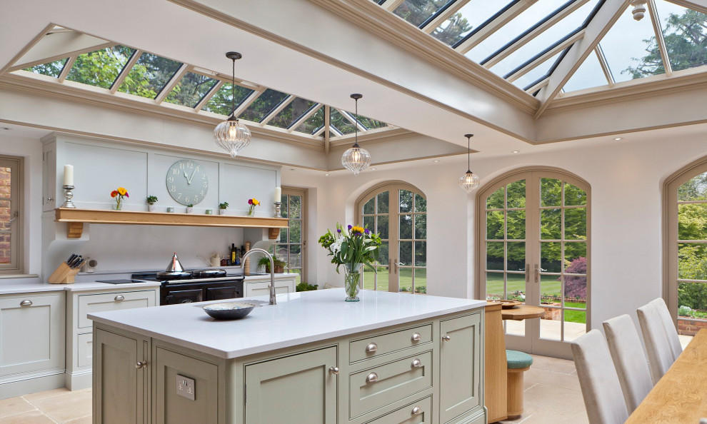 Design ideas for an expansive country galley open plan kitchen in London with an integrated sink, flat-panel cabinets, green cabinets, porcelain flooring, an island, beige floors and a wood ceiling.