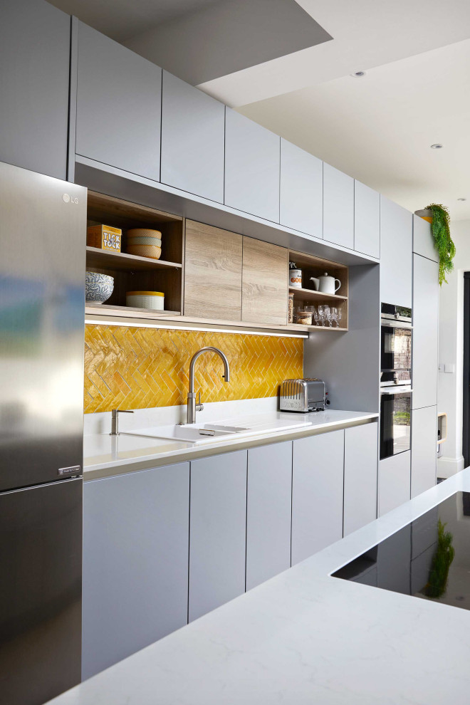 Photo of a large contemporary kitchen/diner in Surrey with flat-panel cabinets, grey cabinets, quartz worktops, yellow splashback, ceramic splashback, an island and white worktops.