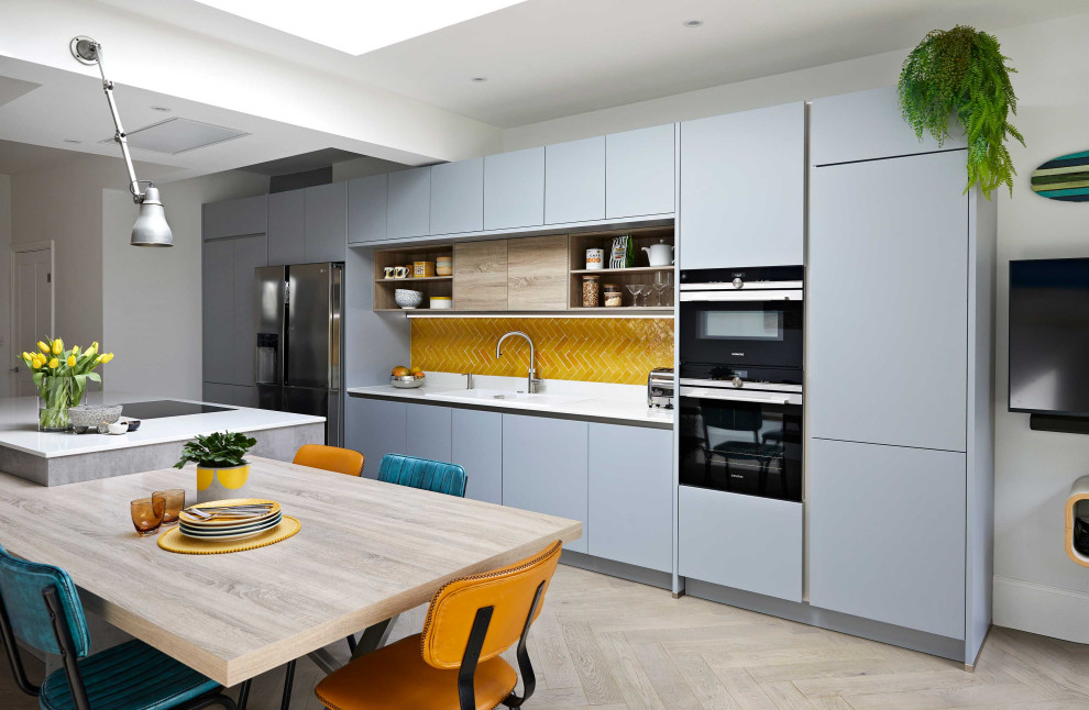 ロンドンにある高級な広いコンテンポラリースタイルのおしゃれなキッチン (フラットパネル扉のキャビネット、グレーのキャビネット、黄色いキッチンパネル、セラミックタイルのキッチンパネル、白いキッチンカウンター) の写真
