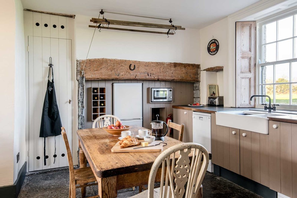 Landhaus Wohnküche ohne Insel mit Landhausspüle, braunen Schränken, Arbeitsplatte aus Holz und weißen Elektrogeräten in Sussex