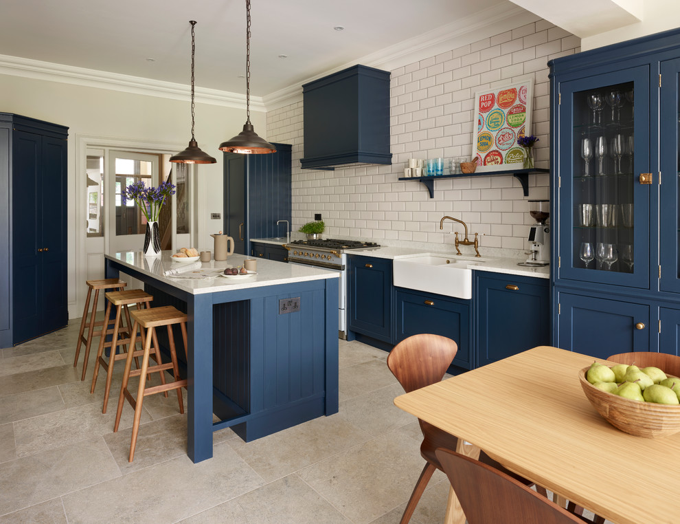Transitional eat-in kitchen photo in Sussex with a farmhouse sink, white backsplash, subway tile backsplash, an island, glass-front cabinets and blue cabinets
