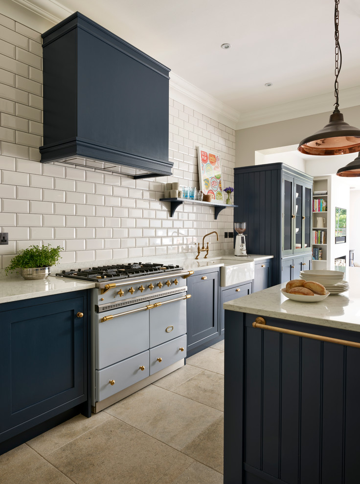 Design ideas for a medium sized traditional kitchen in Sussex with a belfast sink, white splashback, metro tiled splashback, stainless steel appliances and an island.
