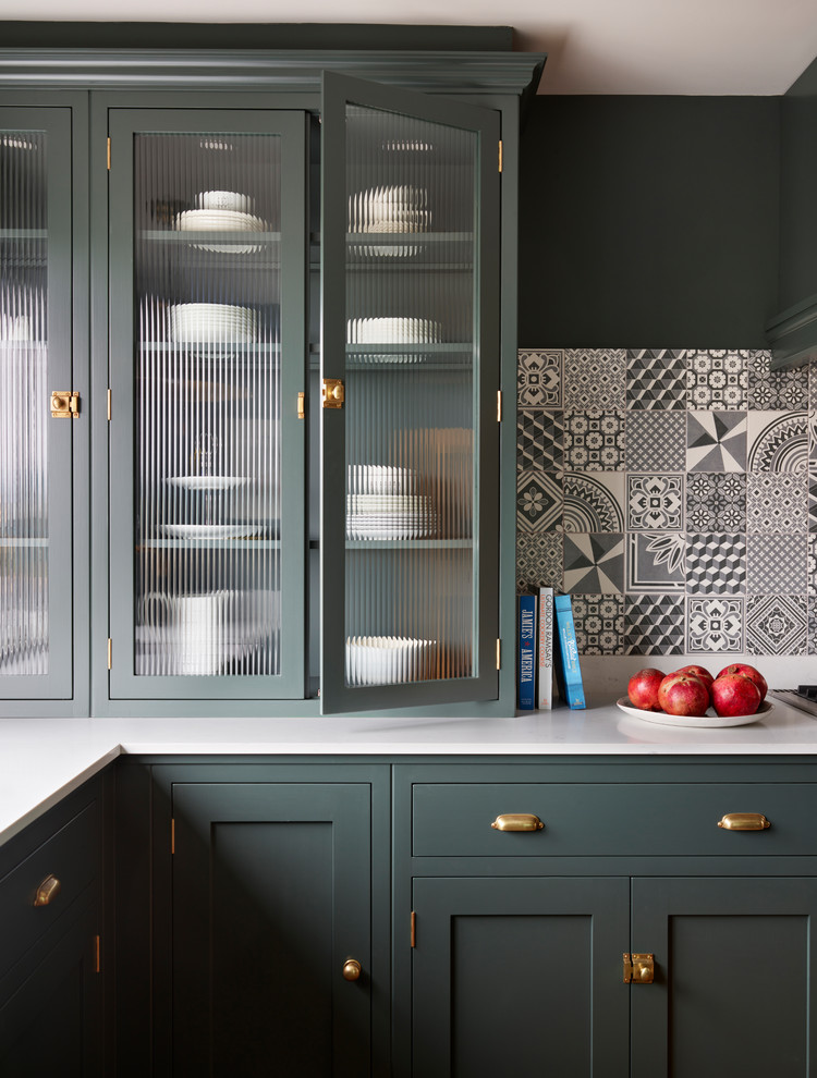 エセックスにある中くらいなトランジショナルスタイルのおしゃれなキッチン (ガラス扉のキャビネット、緑のキャビネット、クオーツストーンカウンター、グレーのキッチンパネル、セラミックタイルのキッチンパネル、アイランドなし) の写真