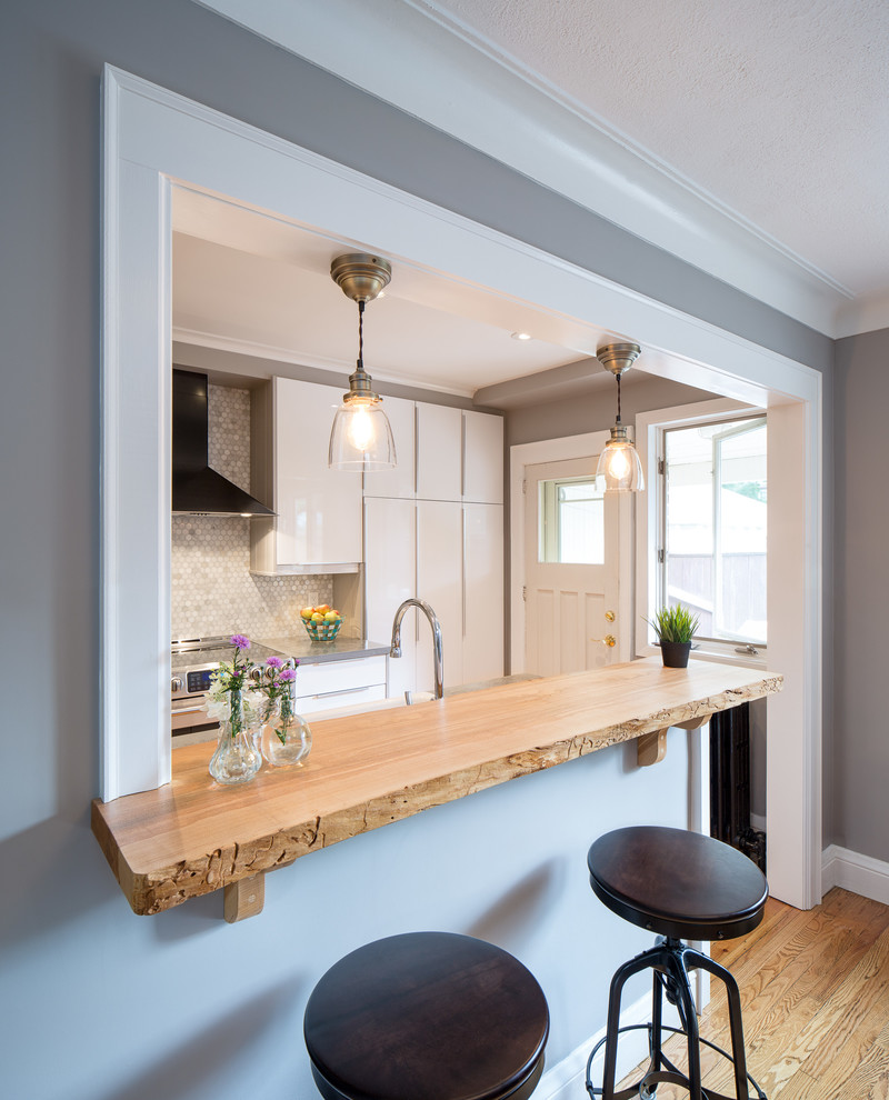 Small traditional galley kitchen/diner in Ottawa with flat-panel cabinets, white cabinets, wood worktops, beige splashback, mosaic tiled splashback, stainless steel appliances and light hardwood flooring.