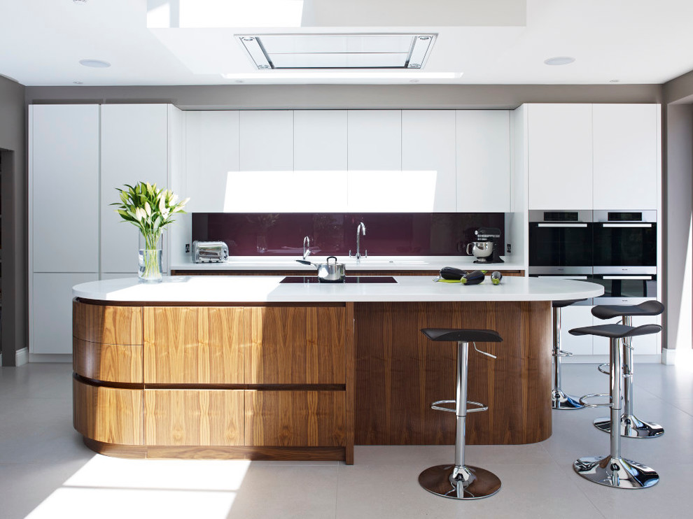 Moderne Küche mit flächenbündigen Schrankfronten, weißen Schränken, Glasrückwand, Küchengeräten aus Edelstahl und Kücheninsel in London