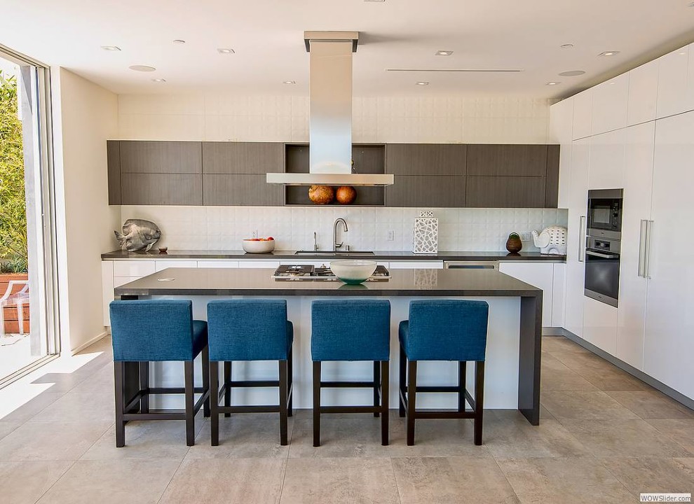 Photo of a medium sized modern galley open plan kitchen in Los Angeles with a submerged sink, beaded cabinets, dark wood cabinets, composite countertops, white splashback, porcelain splashback, stainless steel appliances, ceramic flooring and an island.