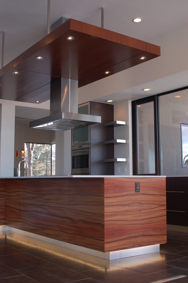 Photo of a medium sized modern l-shaped kitchen/diner in Denver with an island, flat-panel cabinets, medium wood cabinets, composite countertops, integrated appliances, ceramic flooring and a submerged sink.