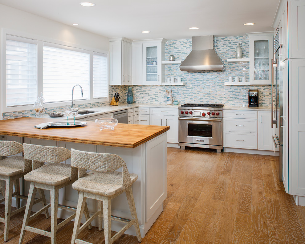 Idéer för att renovera ett mellanstort maritimt kök, med en undermonterad diskho, skåp i shakerstil, vita skåp, marmorbänkskiva, blått stänkskydd, stänkskydd i mosaik, rostfria vitvaror, mellanmörkt trägolv, en halv köksö och brunt golv