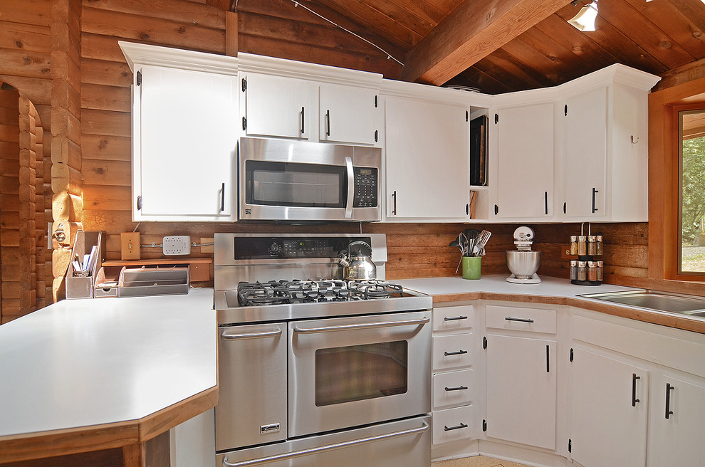 Offene, Mittelgroße Rustikale Küche in U-Form mit Einbauwaschbecken, flächenbündigen Schrankfronten, weißen Schränken, Küchengeräten aus Edelstahl, braunem Holzboden und Kücheninsel in Seattle