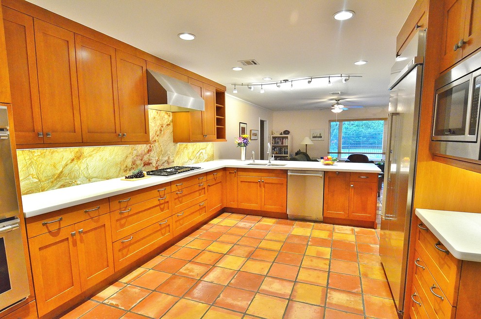 Exempel på ett mellanstort klassiskt u-kök, med en undermonterad diskho, skåp i shakerstil, orange skåp, bänkskiva i kvarts, flerfärgad stänkskydd, stänkskydd i sten, rostfria vitvaror, klinkergolv i terrakotta och en halv köksö