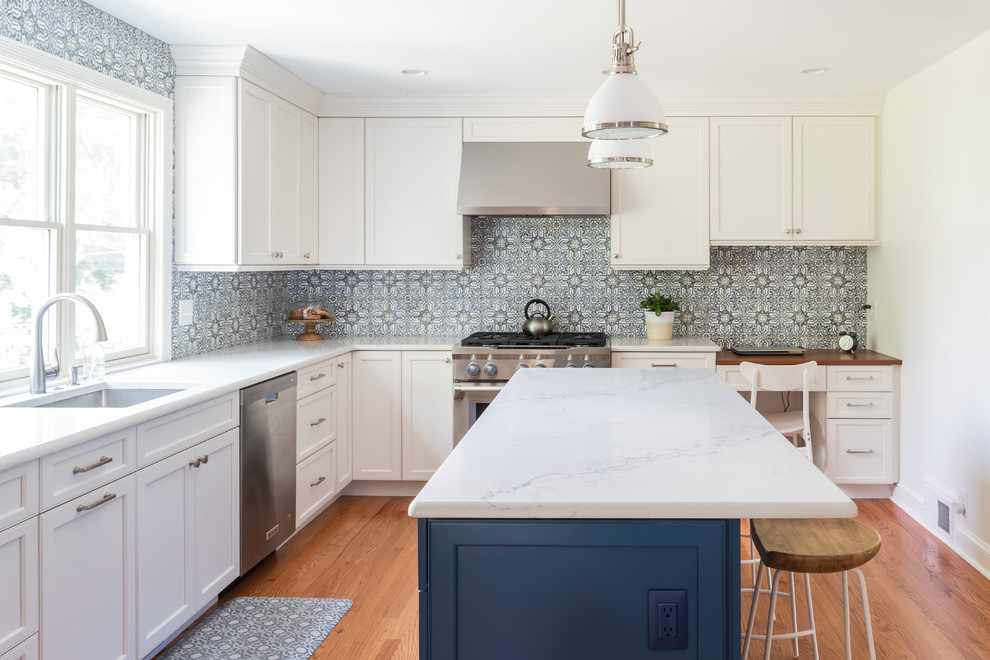 Foto på ett mellanstort vintage vit kök, med en undermonterad diskho, luckor med infälld panel, vita skåp, bänkskiva i kvartsit, flerfärgad stänkskydd, stänkskydd i keramik, rostfria vitvaror, mellanmörkt trägolv, en köksö och brunt golv