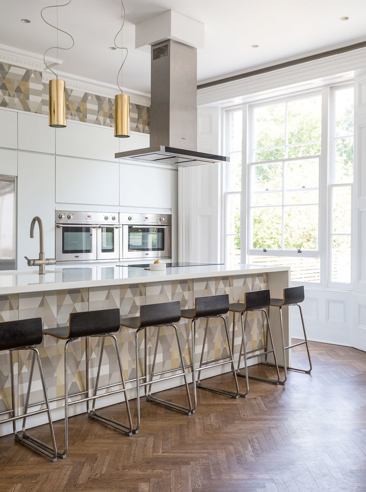 Immagine di un cucina con isola centrale minimal con ante lisce, ante bianche, top in superficie solida e parquet chiaro