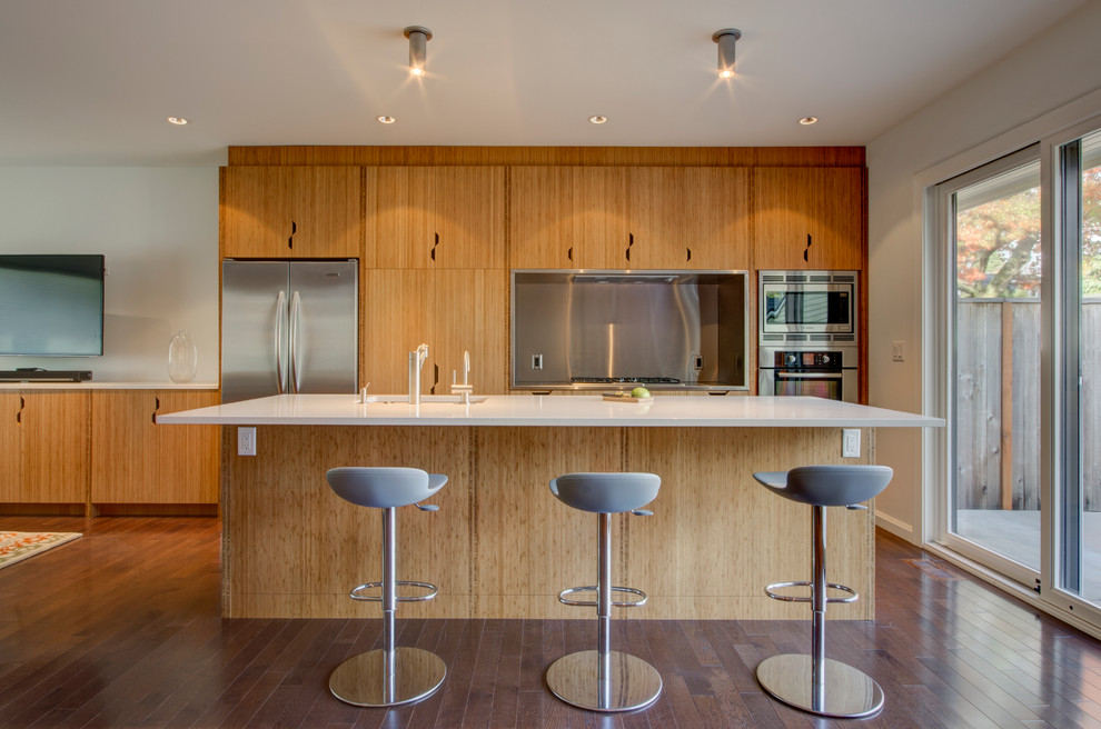 Cette image montre une petite cuisine ouverte parallèle design en bois brun avec un évier encastré, un placard à porte plane, un plan de travail en quartz modifié, un électroménager en acier inoxydable, un sol en bois brun et îlot.